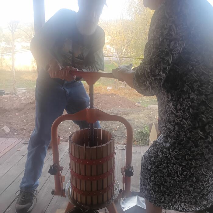 Two members working the hand press together on the deck.